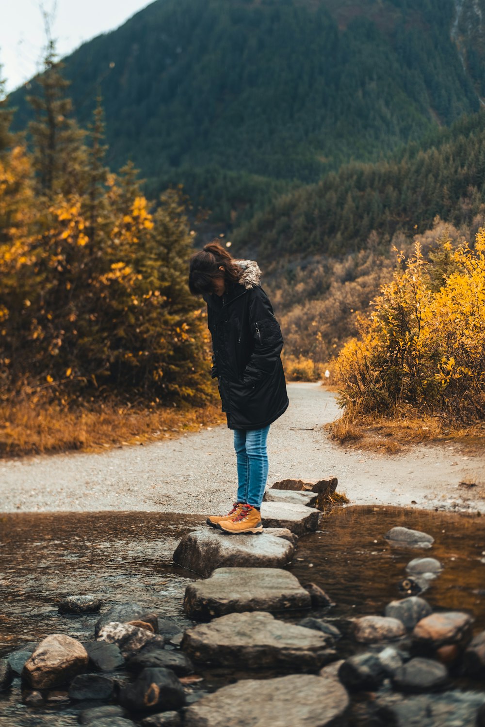 a person standing on a rock path near a body of water