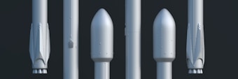 A lineup of five rocket components is displayed vertically against a dark background. Each component shows different stages or sections of a rocket, including what appear to be nose cones and booster stages. The components have a sleek, metallic surface with minimalistic detailing.