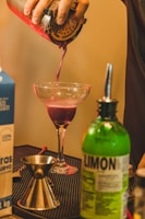 a person pouring a drink into a glass