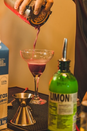 a person pouring a drink into a glass