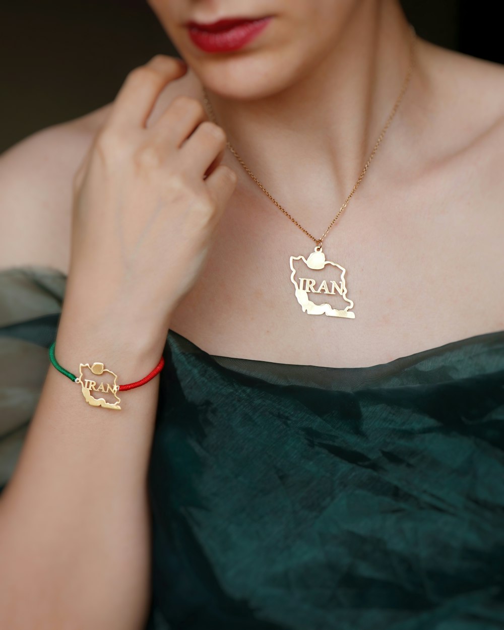 a woman wearing a green dress and a gold necklace