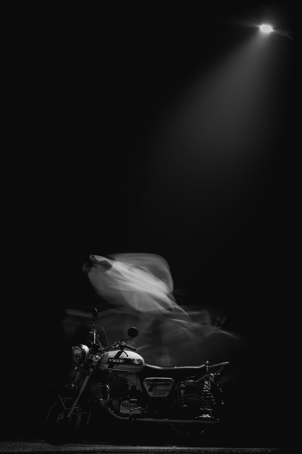 a black and white photo of a motorcycle under a light