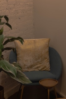 A cozy corner featuring a wooden armchair and a small side table with a plant.