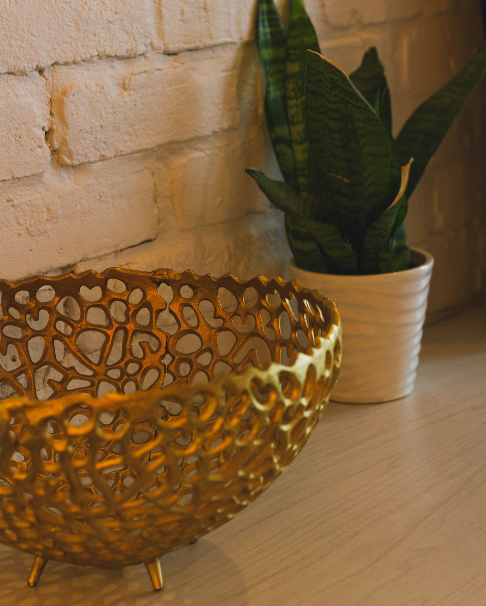 a gold bowl sitting on top of a table next to a potted plant