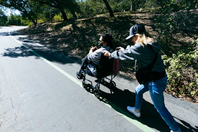 A guide assisting a person in a wheelchair through a scenic park trail.