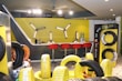A modern showroom displaying various tires arranged neatly. The background features a bar-like area with red stools and a yellow accent wall. Tire racks display differently wrapped tires against a contrasting black and yellow theme. The lighting is bright, enhancing the contemporary design.