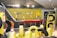 A modern showroom displaying various tires arranged neatly. The background features a bar-like area with red stools and a yellow accent wall. Tire racks display differently wrapped tires against a contrasting black and yellow theme. The lighting is bright, enhancing the contemporary design.