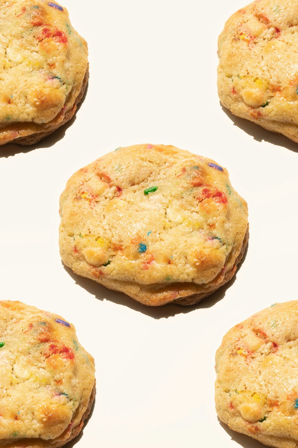 four cookies with sprinkles on a white surface