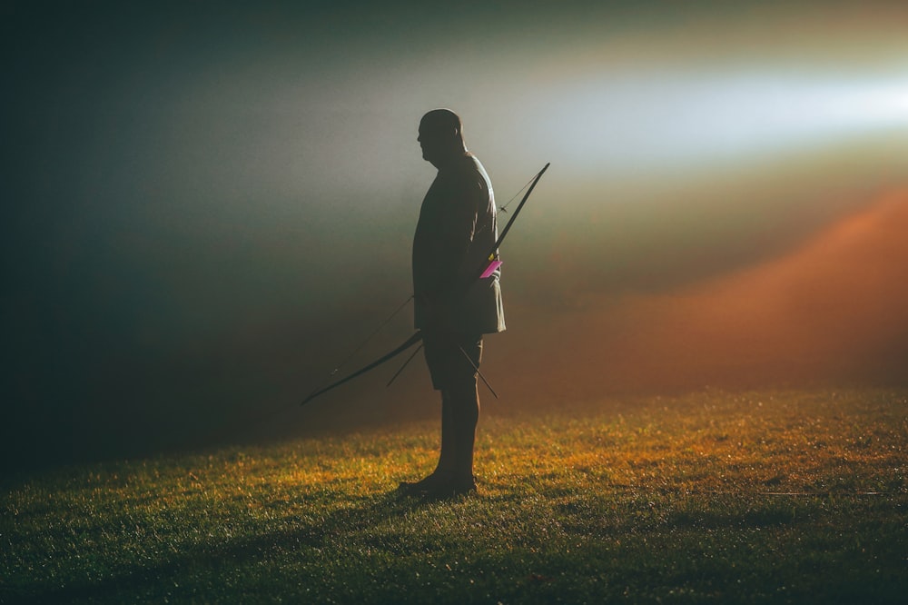 a man standing in a field holding a rifle