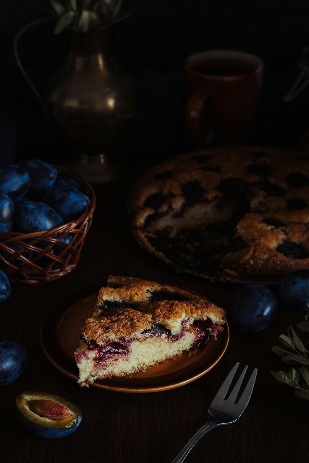 a piece of pie on a plate next to a basket of blueberries