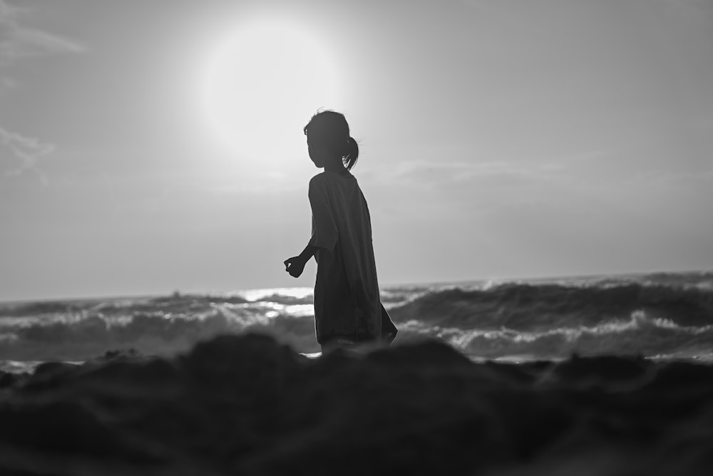 a woman standing on top of a beach next to the ocean