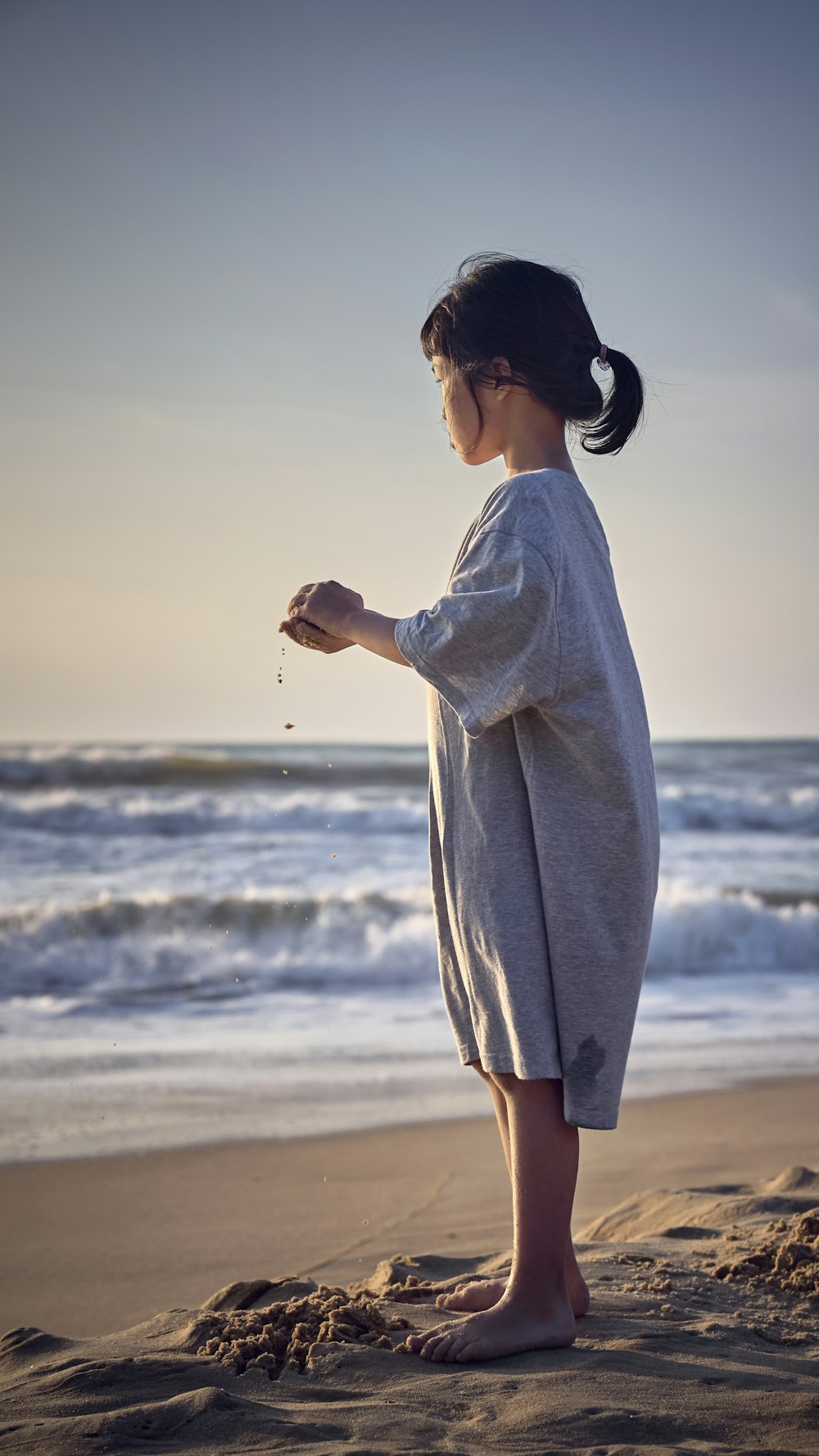 a young girl standing on top of a sandy beach