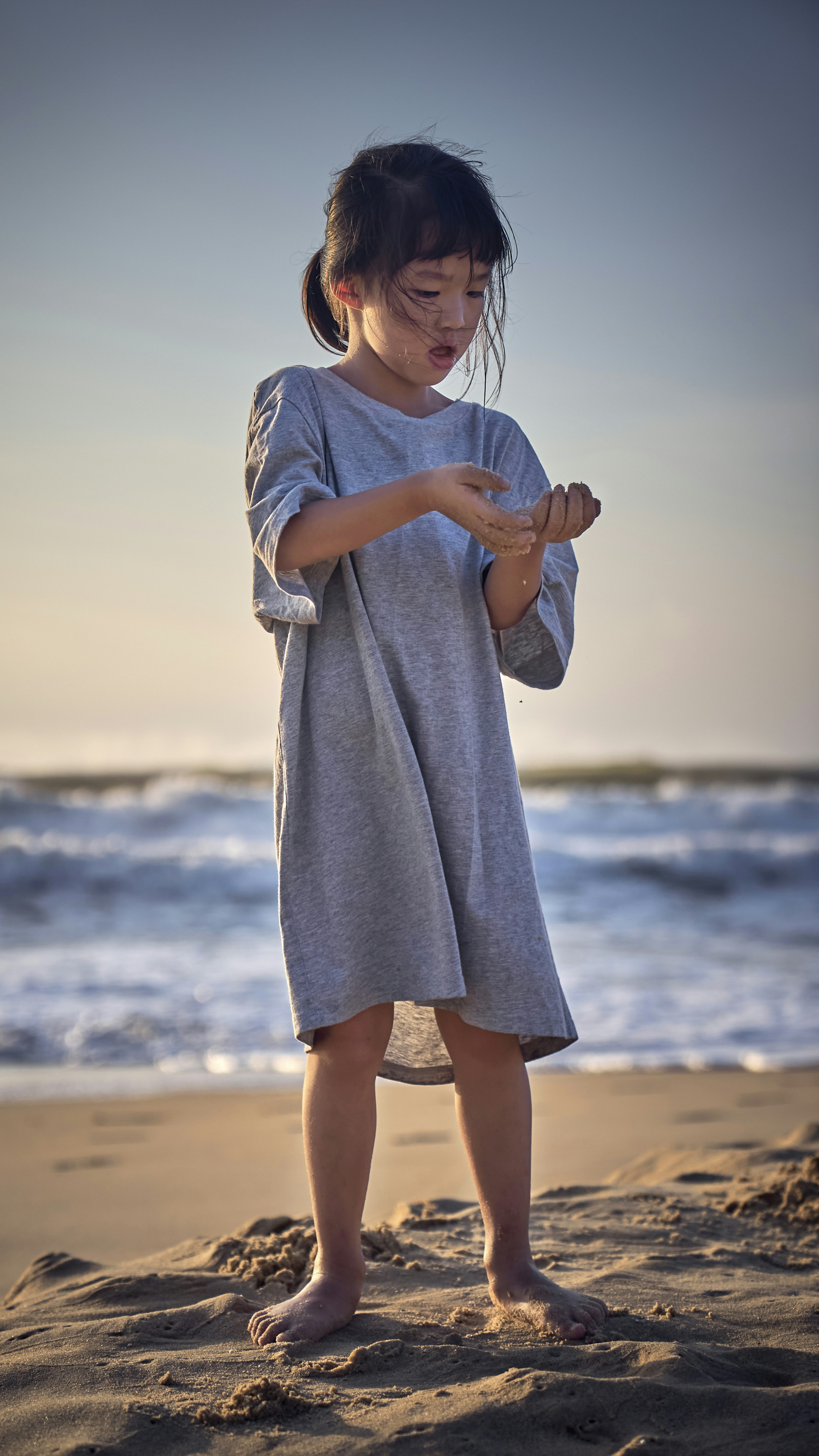 a little girl standing on top of a sandy beach