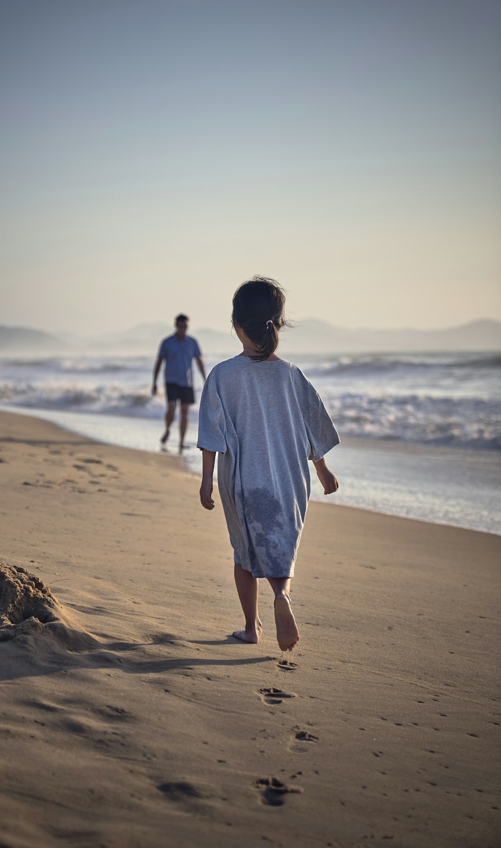 two people walking on a beach near the ocean