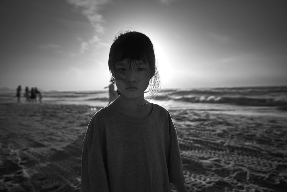 a young girl standing on top of a sandy beach