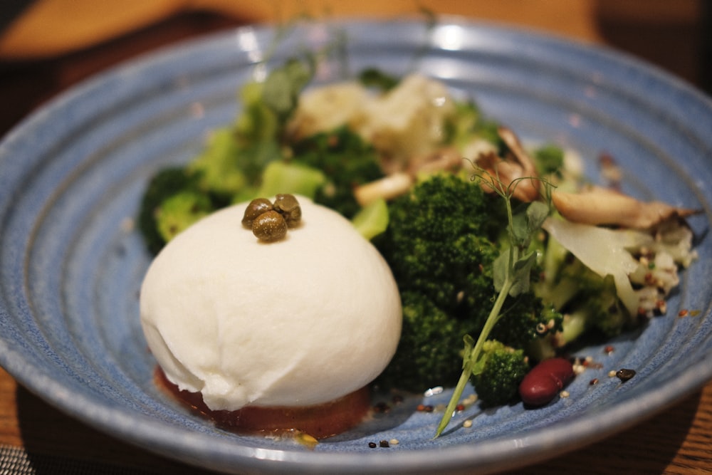 a blue plate topped with broccoli and a scoop of ice cream