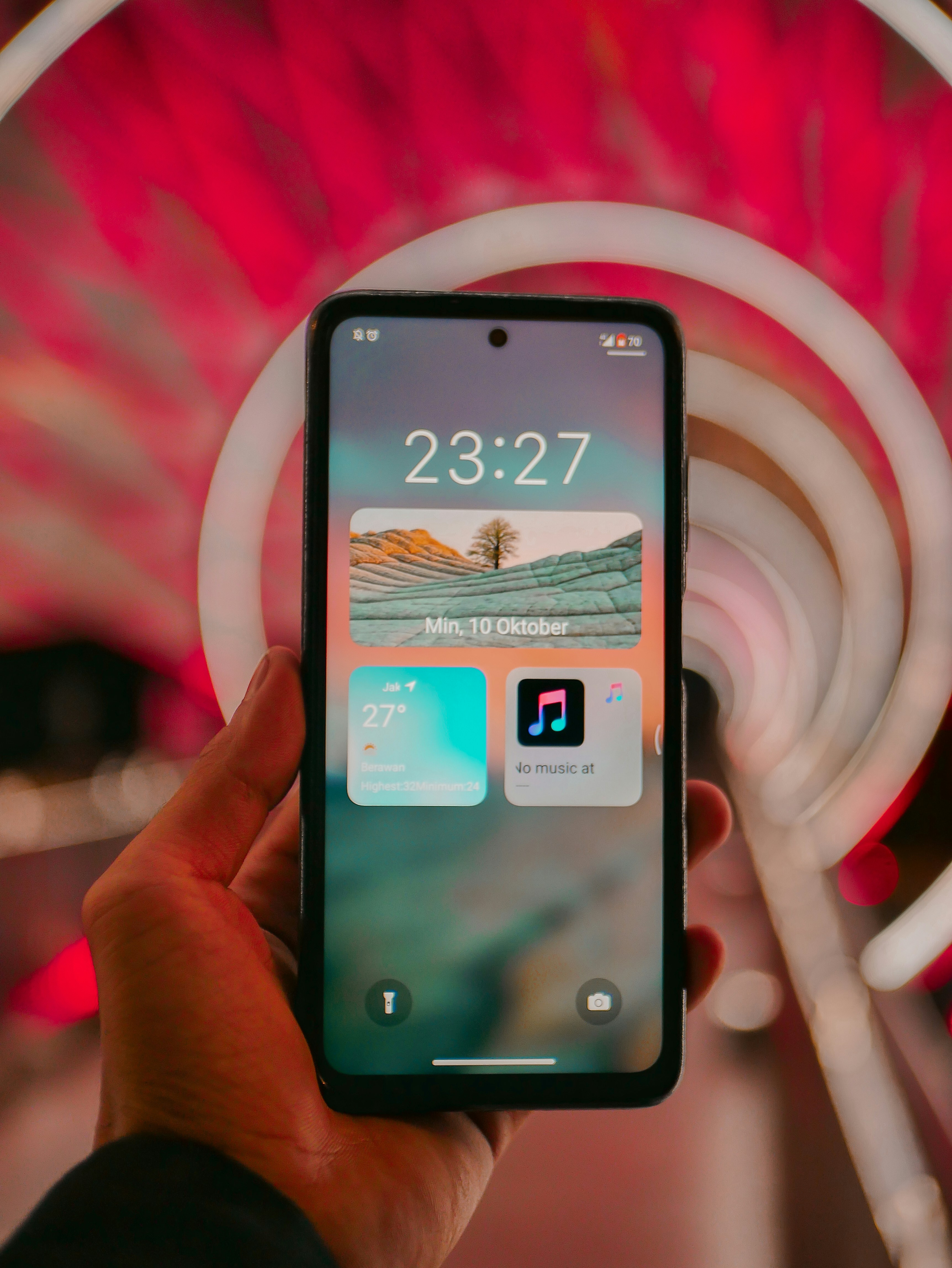 a person holding up a smart phone in front of a ferris wheel