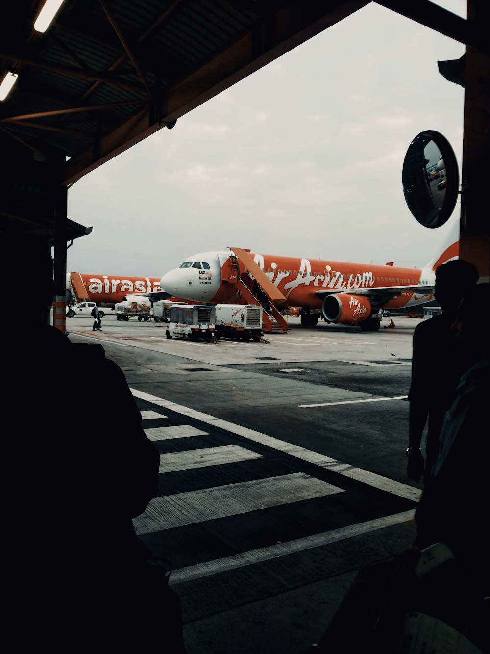 an orange and white jet airliner sitting on top of an airport tarmac