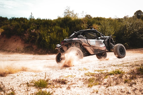 Close-up of a rugged buggy speeding across rocky desert terrain with mountains in the background.