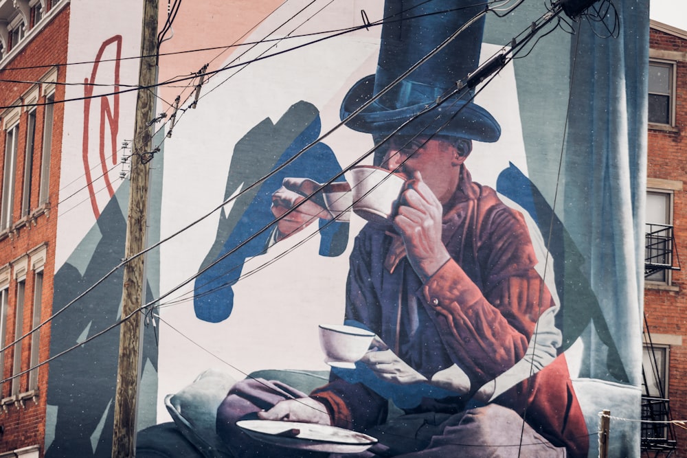 a mural on the side of a building of a man drinking a cup of coffee