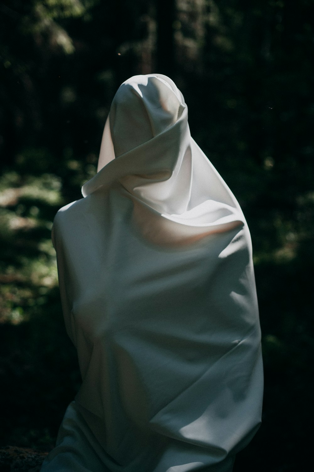 a person wrapped in a white cloth in the woods
