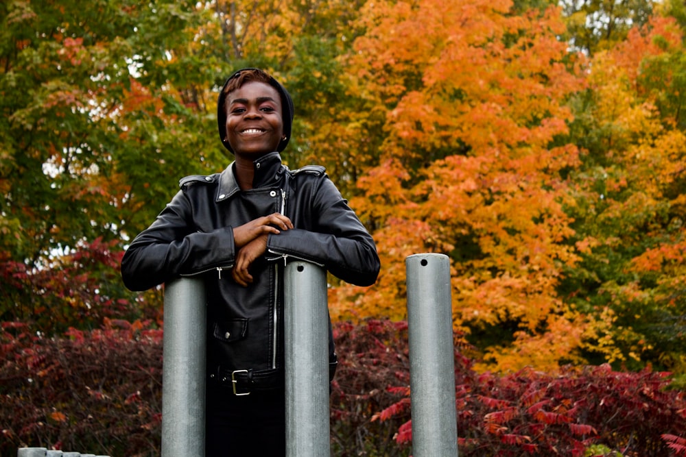 a woman in a leather jacket standing behind two metal poles