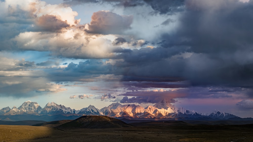 a mountain range under a cloudy sky with mountains in the background