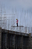 A confident engineer in a safety helmet reviewing blueprints beside iron rods
