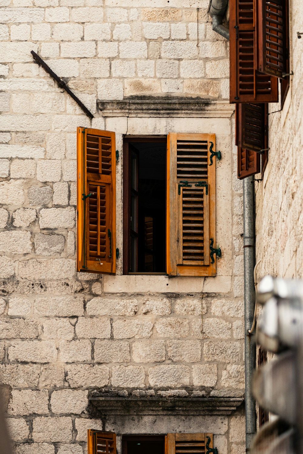 ein Backsteingebäude mit hölzernen Fensterläden und Fenstern