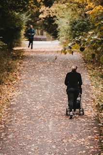 Mums walking together along a leafy trail, pushing strollers and chatting.