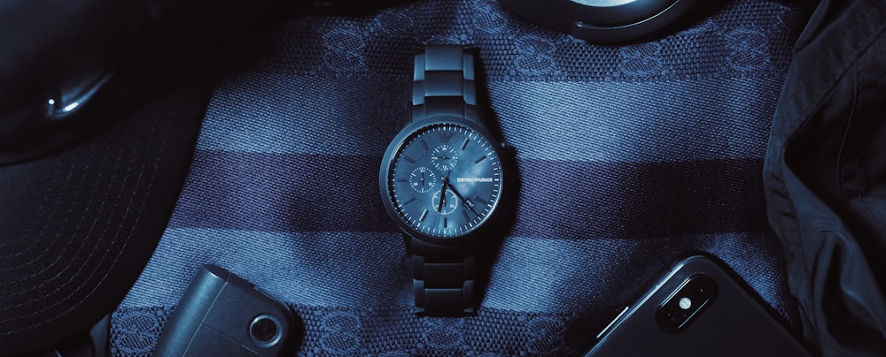 Un reloj sentado encima de una tela azul a cuadros
