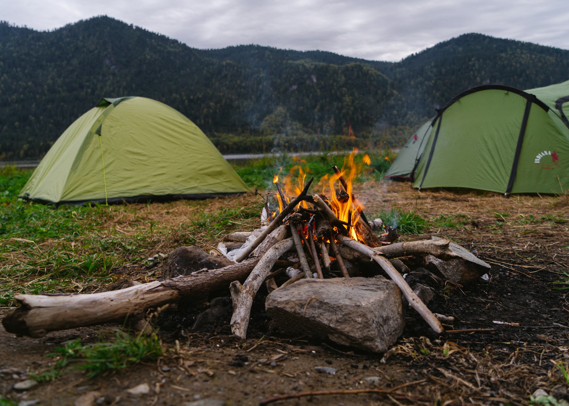 a camp site with a camp fire and tents in the background