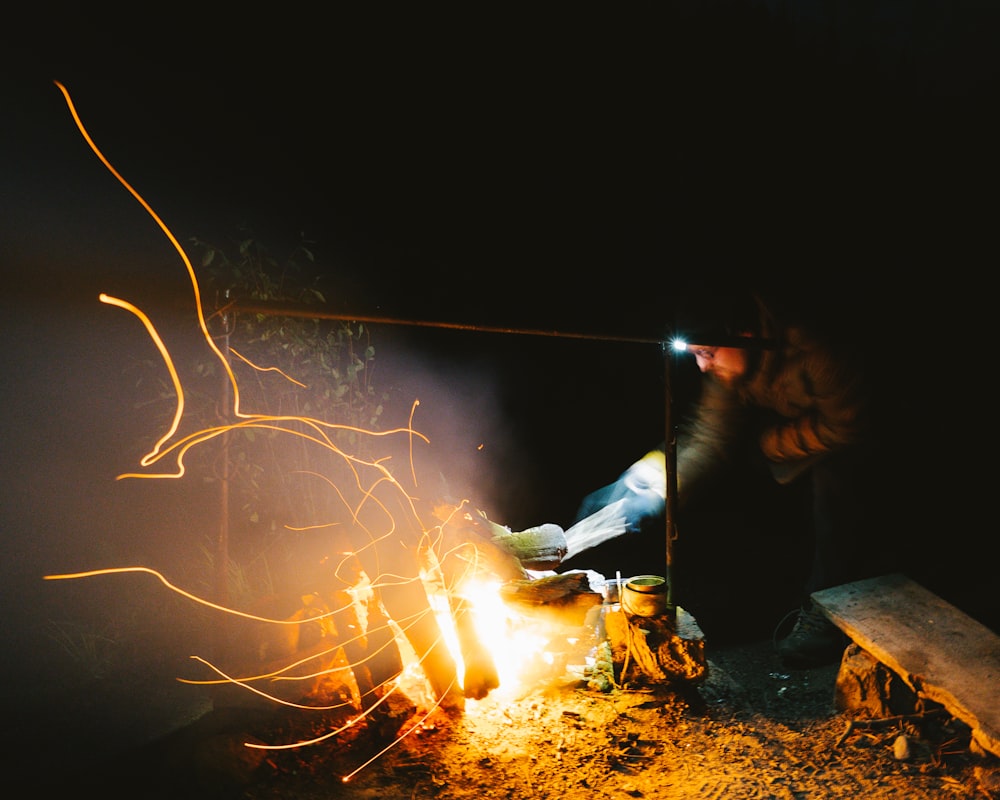a person standing over a fire in the dark