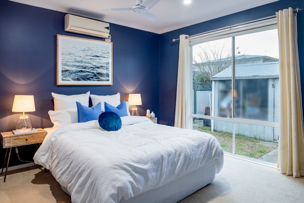 a bedroom with blue walls and a white bed