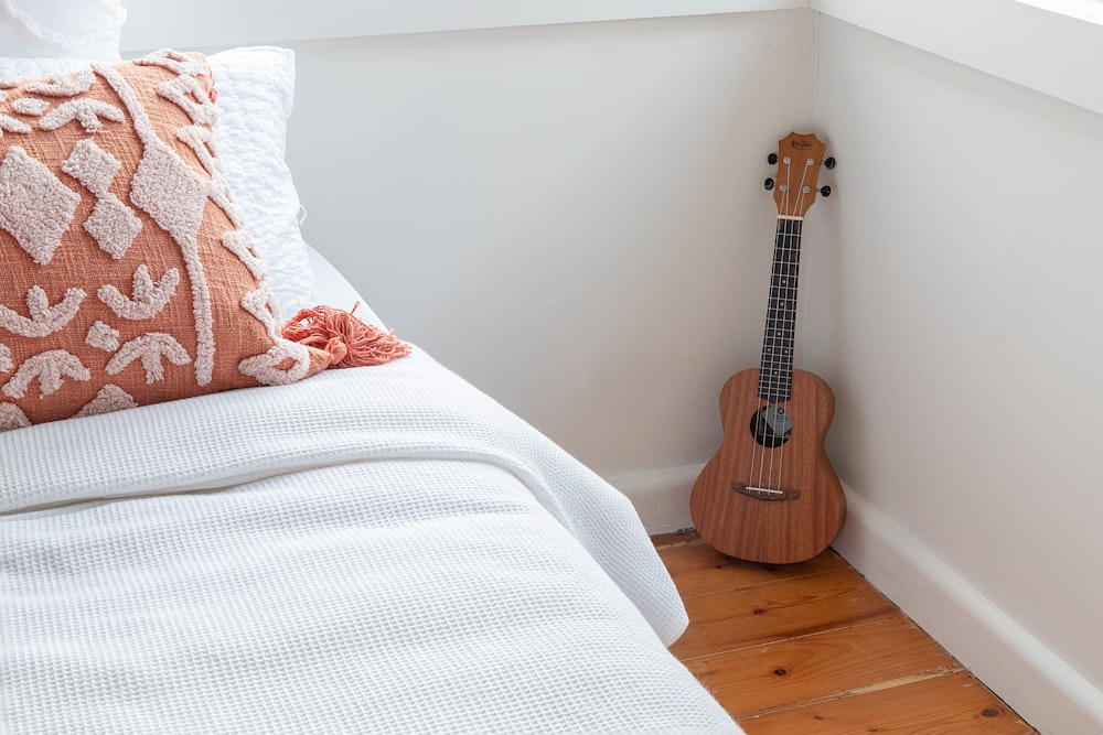 a ukulele sitting on the floor next to a bed