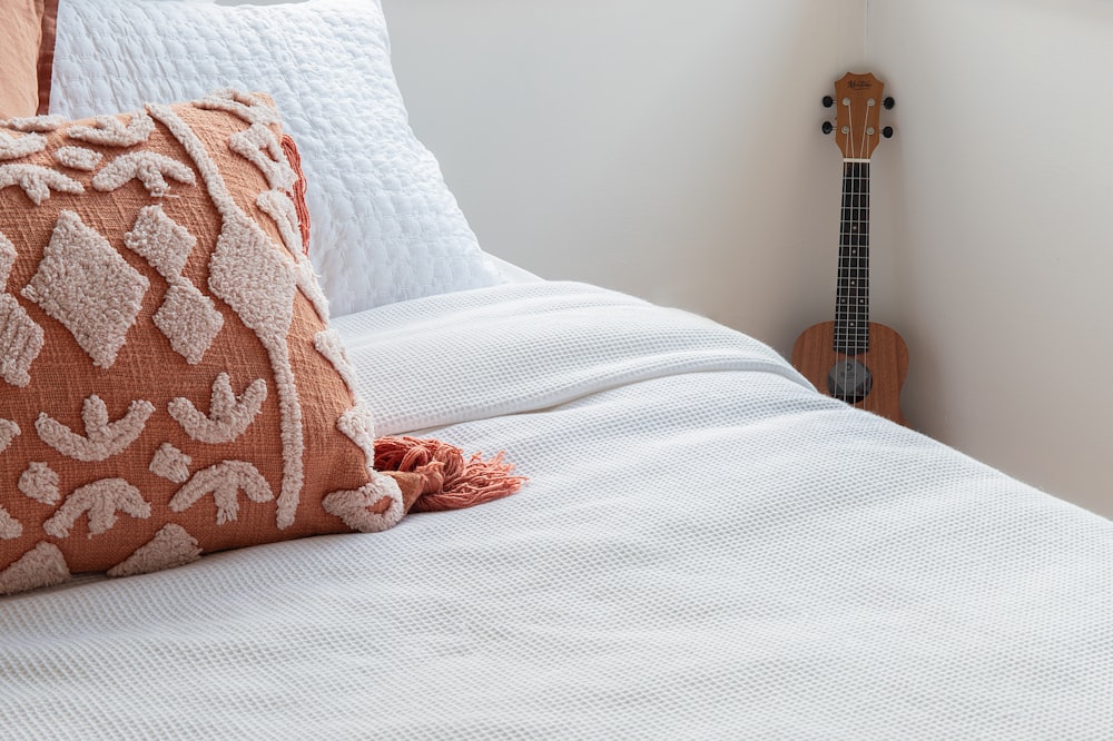 a bed with a white comforter and a guitar on the wall