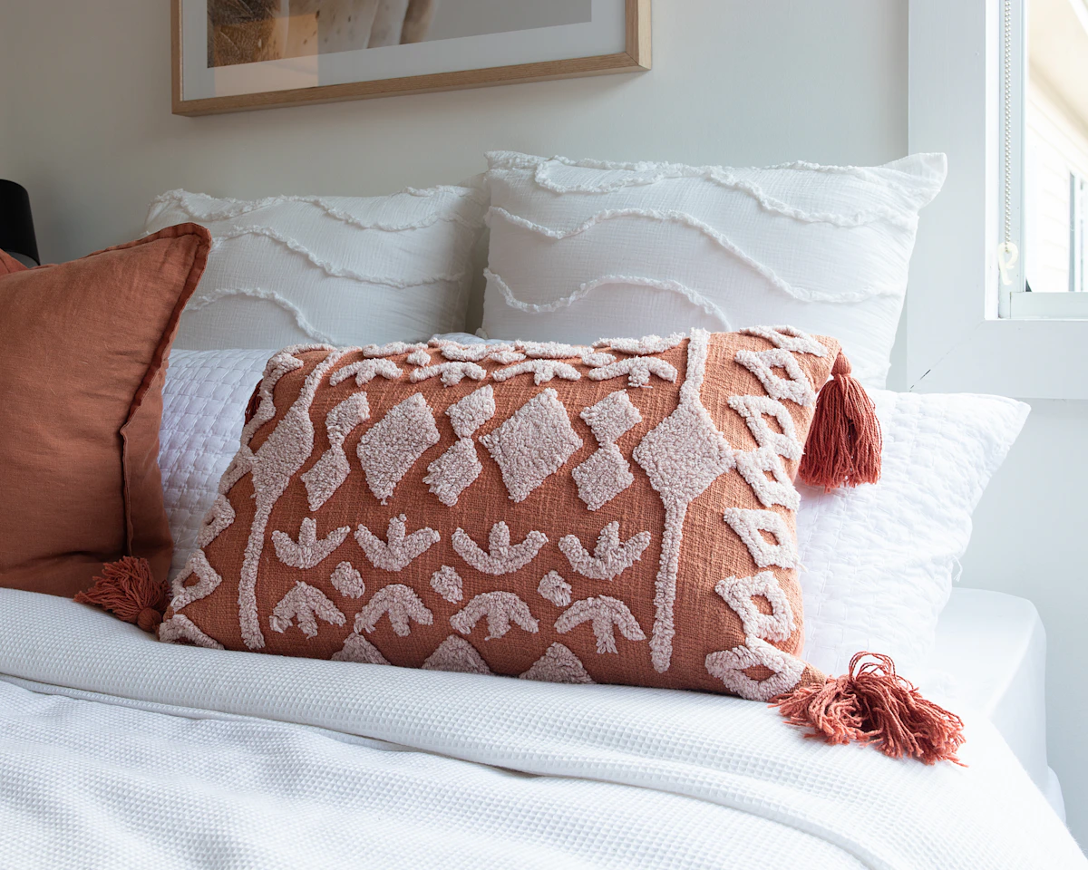 Textured pillow shams and decorative bed pillows arranged on white bedding