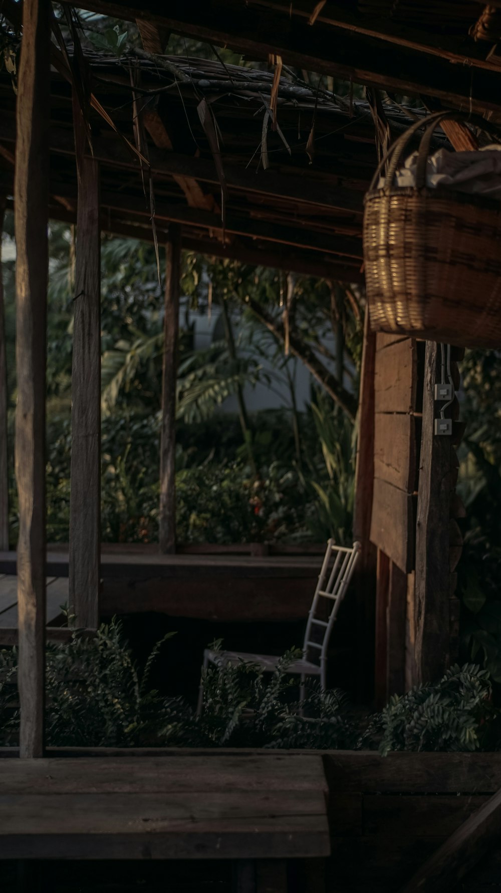 a chair sitting under a wooden roof in a garden