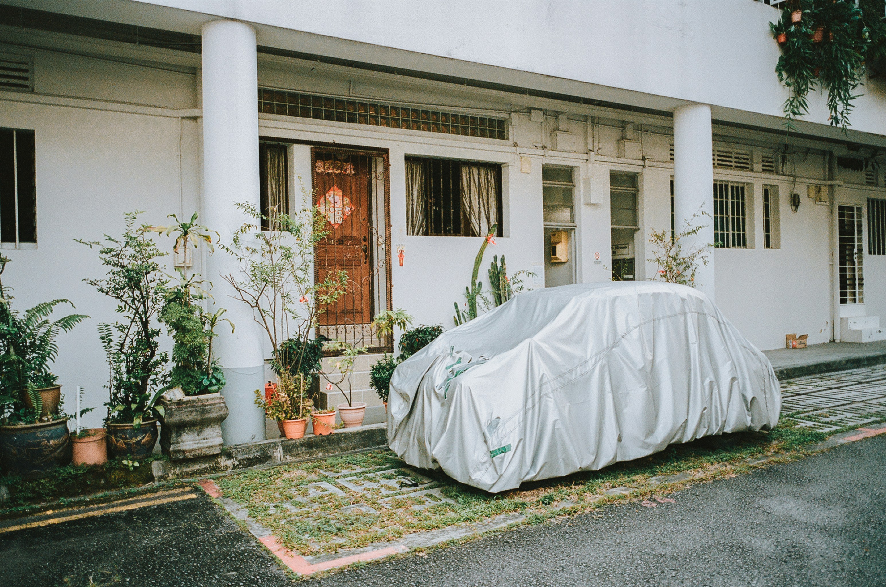 un'auto coperta da un telo parcheggiata davanti a una casa