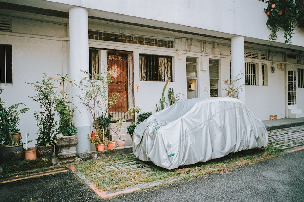 a car covered in a tarp parked in front of a house