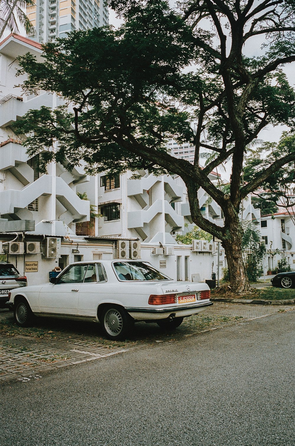 a white car parked in front of a tall building