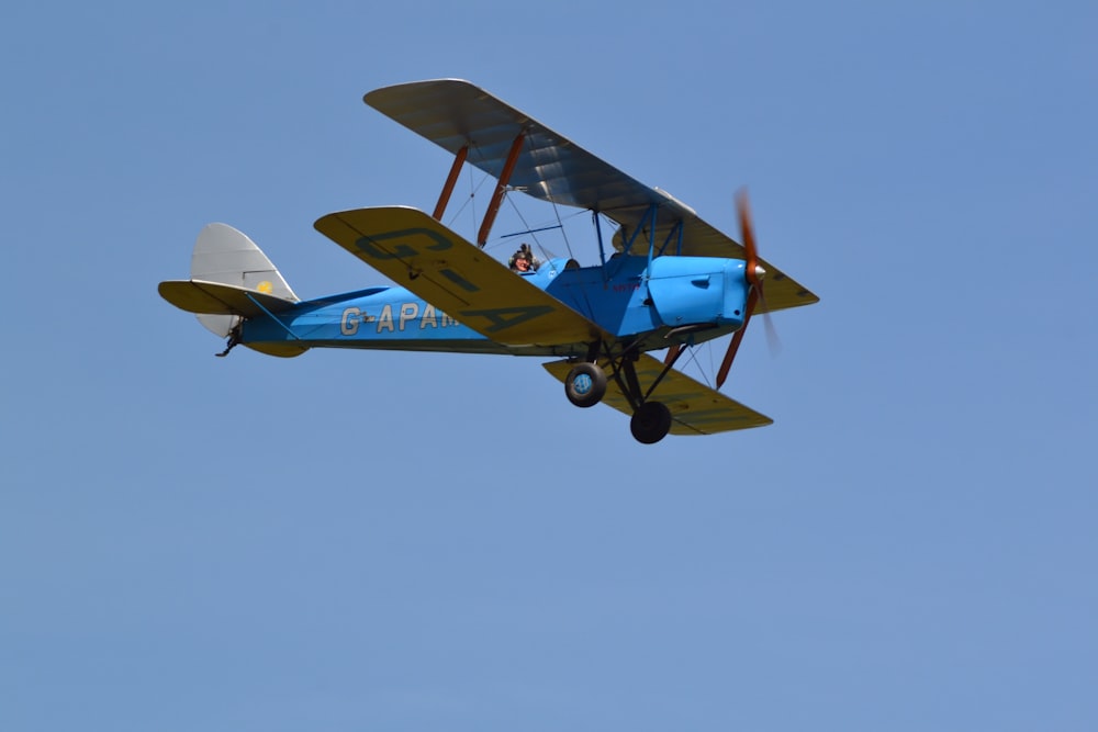 Un pequeño avión azul y amarillo volando en el cielo