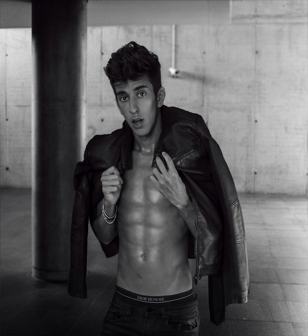 a shirtless man in a leather jacket posing for a picture