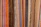 Colorful woven textiles with vertical stripes in various shades including blue, red, yellow, orange, black, and beige. The fabric appears to have a textured surface, typical of traditional woven materials.