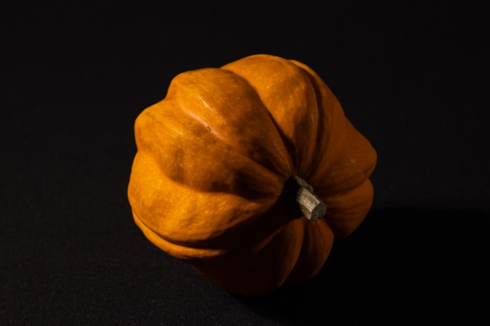 a small orange pumpkin sitting on a black surface