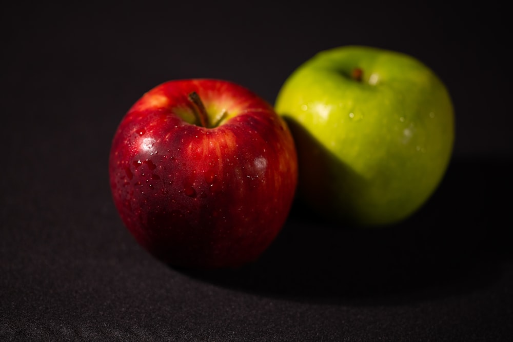 a green and a red apple on a black background