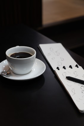A blank page with a pencil and an unmade cup of coffee on a wooden table.