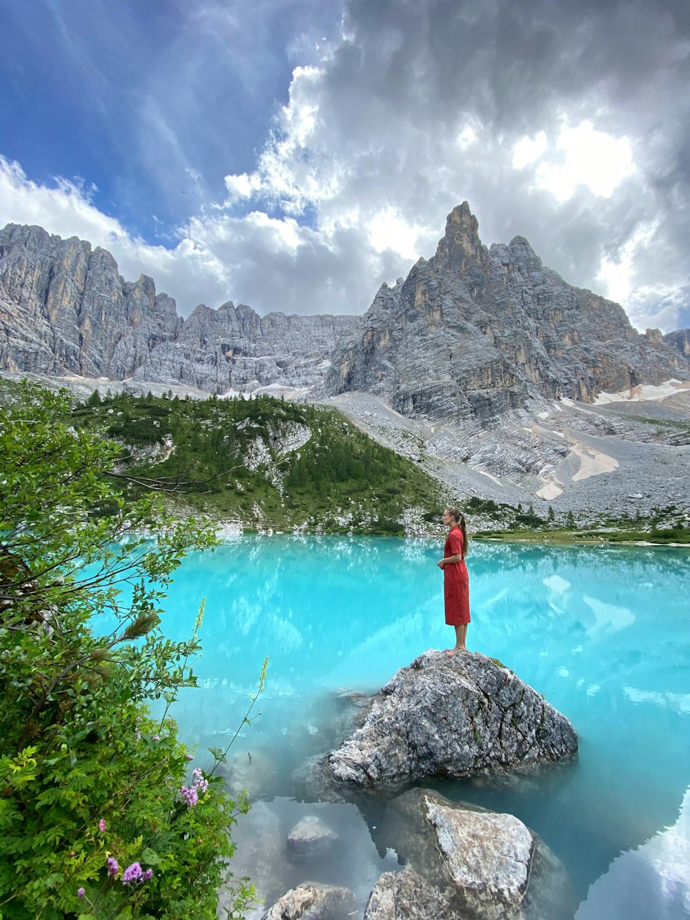 Una persona parada en una roca frente a un lago