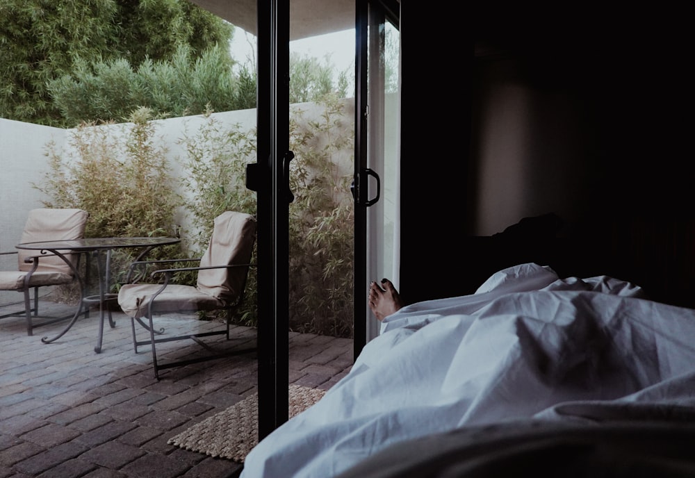 a person laying in a bed next to a sliding glass door