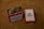 A red metal tin labeled 'Dad Grass' filled with dried hemp flowers sits next to a matching rectangular box. Both items feature vintage-style packaging design.